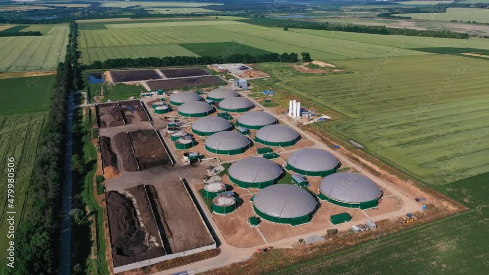 Modern agribusiness plant for green fuel production. Futuristic biogas complex locating in vast fields. Aerial perspective.
