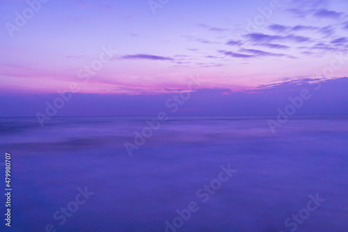 Beautiful long exposure seascape of smooth wavy sea and clound. Pink horizon with first sunset sky.