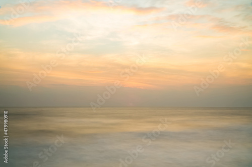 Beautiful long exposure seascape of smooth wavy sea and cloud. orange horizon with first sunrise sky.