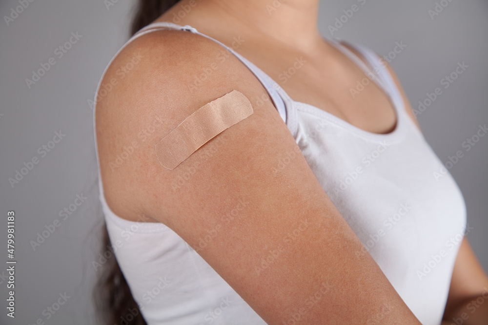 Woman putting adhesive bandage on arm.