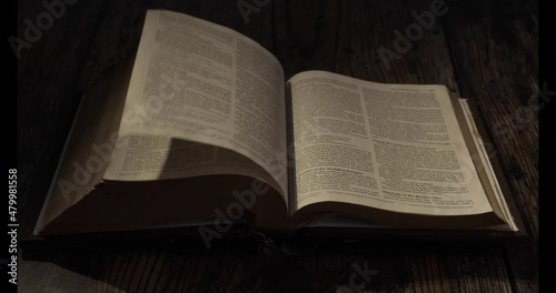 A  page in the bible is being turned over, contrast Night atmosphere