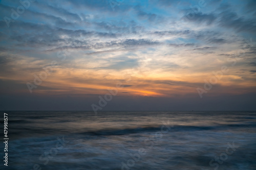Fototapeta Naklejka Na Ścianę i Meble -  Beautiful long exposure of an amazing sunset from smooth wavy sea and cloud. orange horizon with sunrise sky.