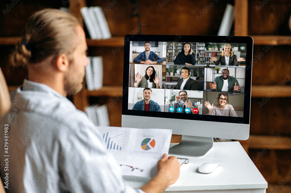 Online briefing, virtual business meeting. View over the shoulder of a company employee communicating with a group of multi-ethnic colleagues via video conference, analyzing financial statements Online briefing, virtual business meeting. View over the shoulder of a company employee communicating with a group of multi-ethnic colleagues via video conference, analyzing financial statements