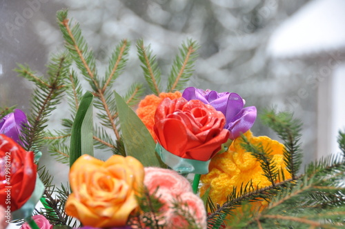 Arrangement of artificial flowers and spruce branches on the windowsill