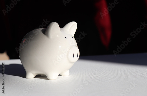 Money savings concepts Piggy bank symbol of saving money on white table with shadow from natural dark light background. Concept for loan, financial, mortgage, real estate investment, taxes and bonus. photo