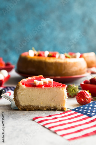 Cheesecake slice, New York style classical cheese cake with strawberry on blue background. Slice of tasty cake on white plate