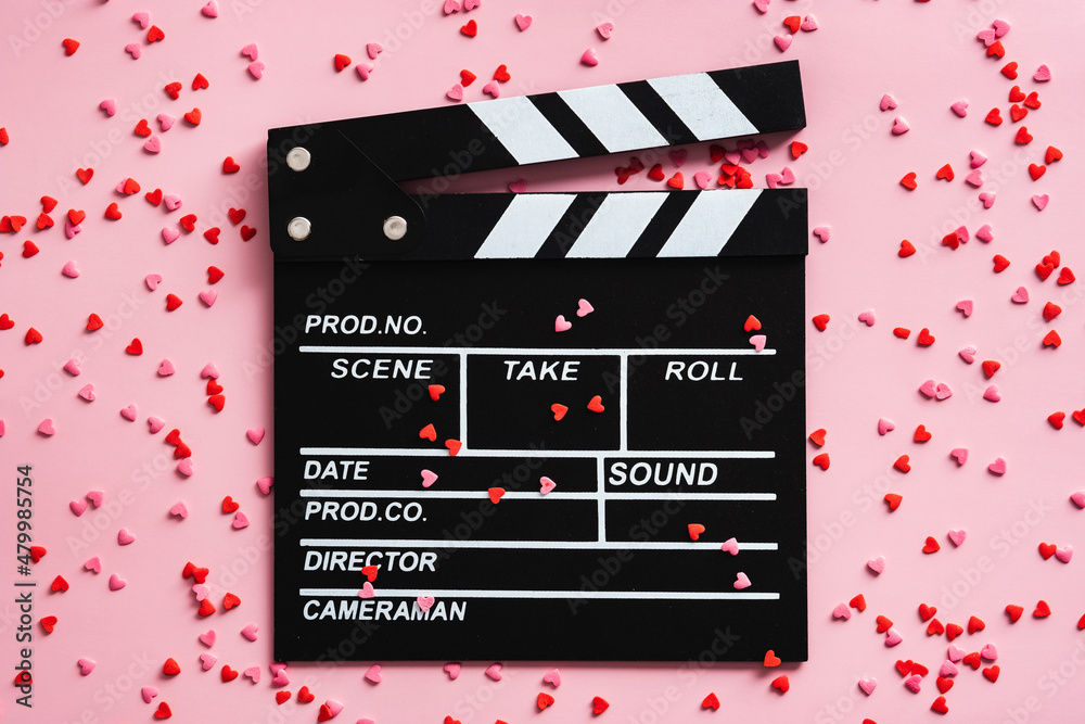 Movie clapper board and confetti on pink background. Romantic movie, love concept.