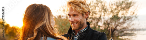 White couple smiling and looking at each other while standing outdoors