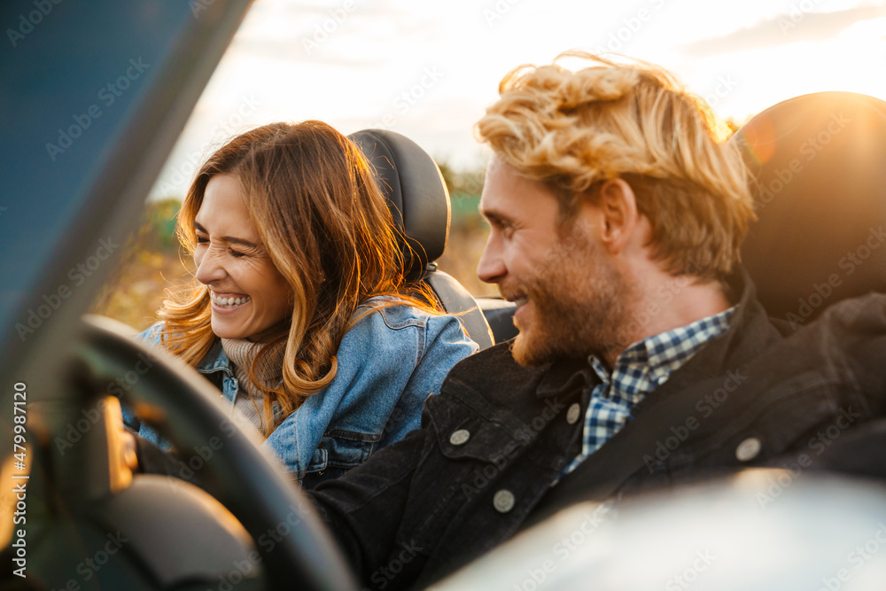 Leinwandbild Motiv - Drobot Dean : White couple smiling together while driving in car during trip
