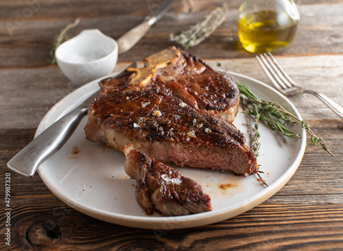 Foto Pan fried porterhouse steak on a plate with salt and pepper seasoning and cross
