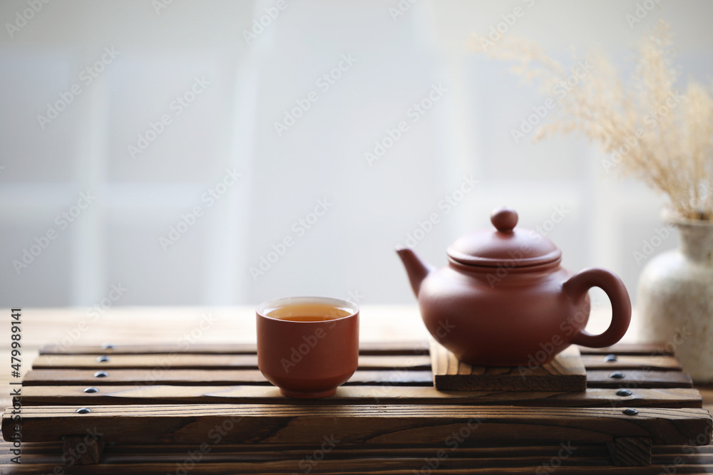 Fotka „Pottery tea pot and tea cup and pot of dry grass on wooden tray“ ze  služby Stock | Adobe Stock