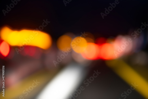 Blurred moving lights on a german Autobahn seen through the windshield while driving at night in total darkness. Traffic lights, construction site flash lights and lines in red, yellow and orange.