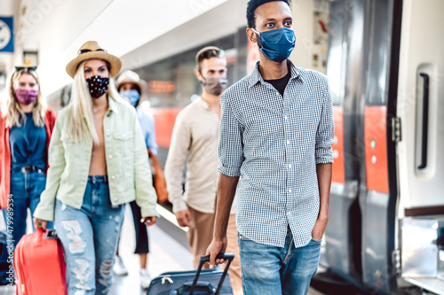 Crowd of people walking at railroad station platform covered by protective face mask - Negative travel concept with young students on omicron variant outbreak emergency - Focus on right guy