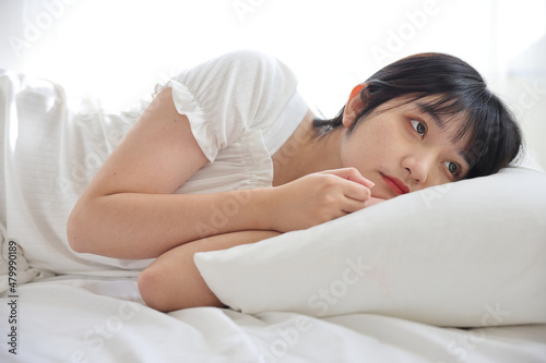 Beautiful young Asian woman sleeping on bed relaxing in the morning light with white room