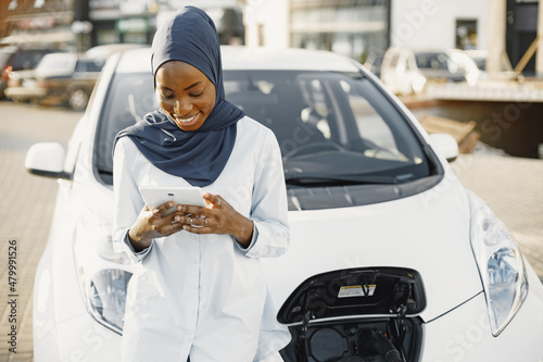 Afrian american woman using tablet at white car photo