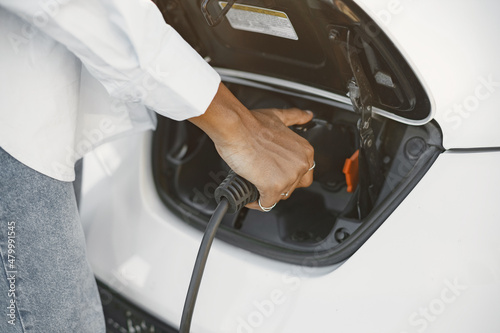African American girl charging electro car at the electric gas station © prostooleh