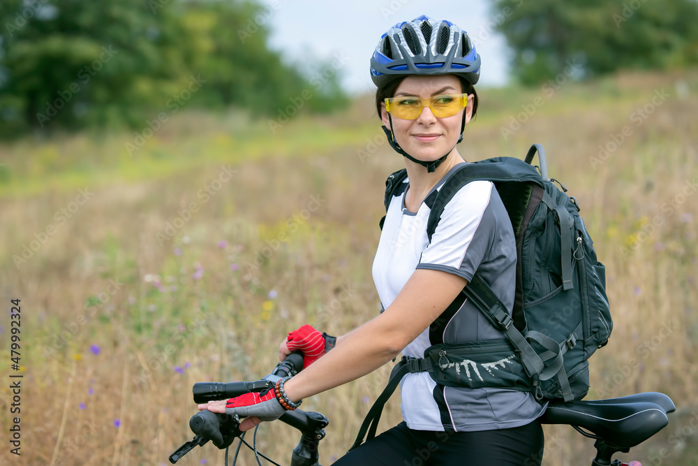 Naklejka premium beautiful and happy woman cyclist rides a bicycle on the road in nature. Healthy lifestyle and sports. Leisure and hobbies