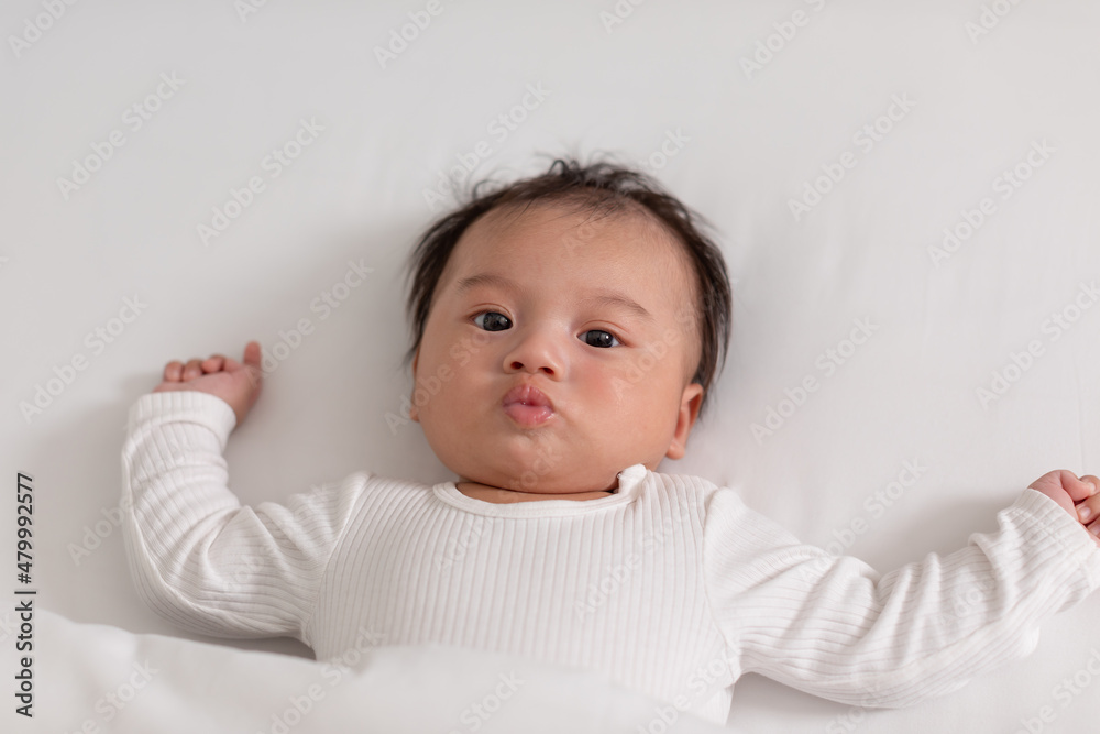 Top view happy newborn baby lying on a white bed and blanket comfortable and safety.Cute Asian newborn looking around on bed.Newborn Baby Care concept Top view happy newborn baby lying on a white bed and blanket comfortable and safety.Cute Asian newborn looking around on bed.Newborn Baby Care concept