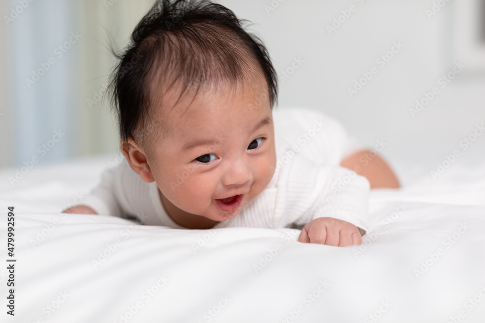 Newborn baby 3 month laying on stomach developing neck control .tummy time for strengthen baby neck and shoulder muscles.Cute infant lying crawling on white bed happiness and fun.Tummy Time Concept Newborn baby 3 month laying on stomach developing neck control .tummy time for strengthen baby neck and shoulder muscles.Cute infant lying crawling on white bed happiness and fun.Tummy Time Concept