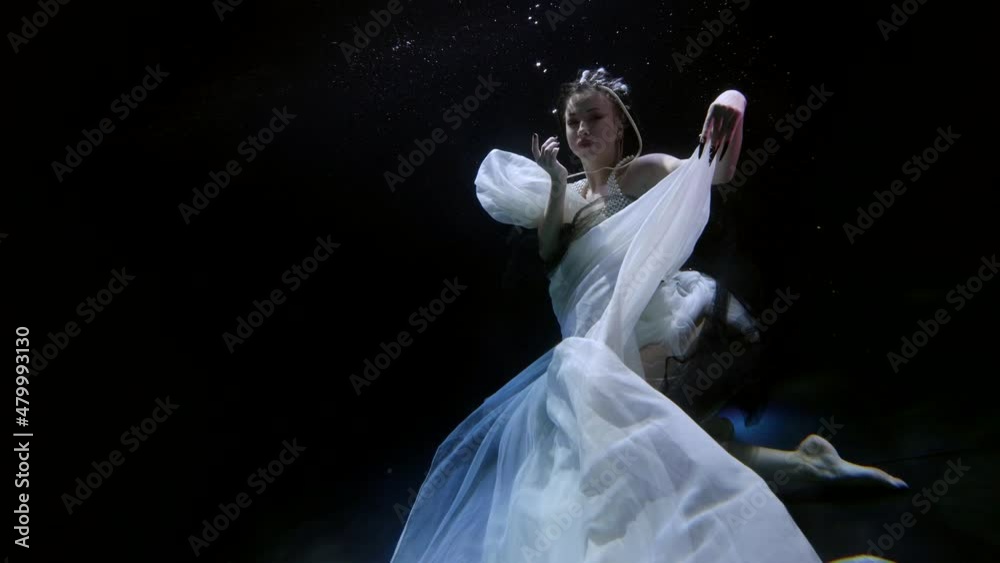 graceful lady is swimming in deepness of dark magic sea, romantic and mysterious female figure
