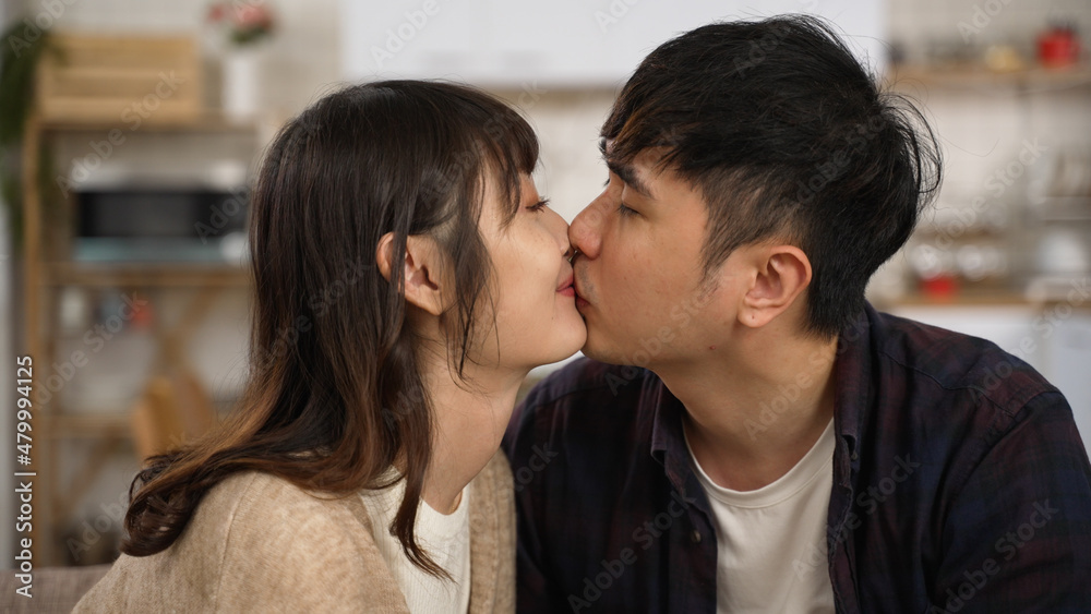 closeup of asian romantic young couple gently kissing on lips at home. the woman looking at her boyfriend with a smile closeup of asian romantic young couple gently kissing on lips at home. the woman looking at her boyfriend with a smile