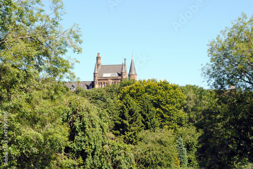 Billede på lærred Roof of Old Stone Building with Circular Tower seen over Woodland against Blue S