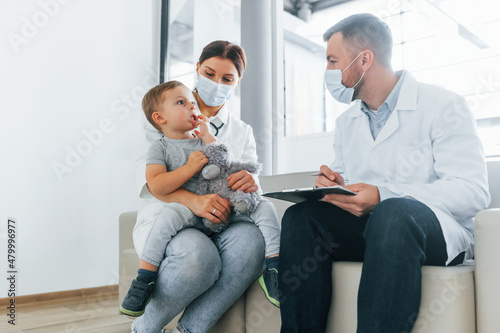 With little boy that being examined. Two doctors in white coats is in the clinic working together