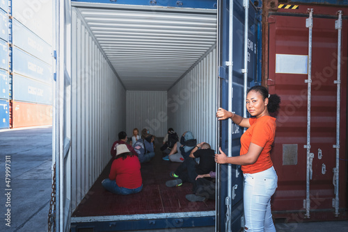 An African women Opening the door of a container, inside of which several people were sitting, to human trafficking and illegal immigration concept.