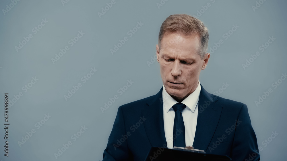 Businessman in formal wear holding clipboard isolated on grey. Businessman in formal wear holding clipboard isolated on grey.