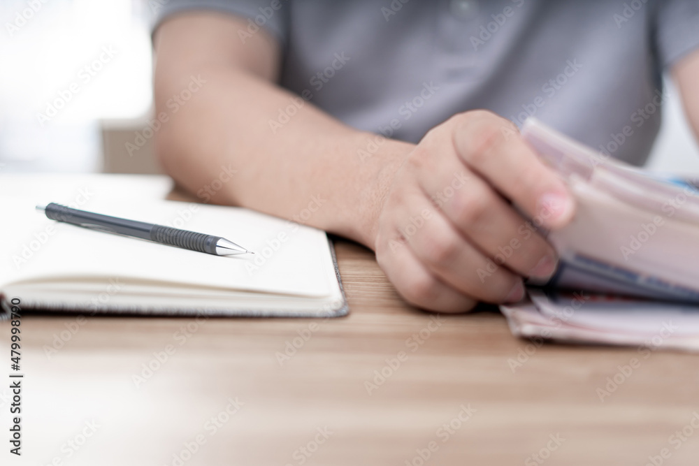 Close up pen on notebook and a man looking newspaper on the wood table Close up pen on notebook and a man looking newspaper on the wood table