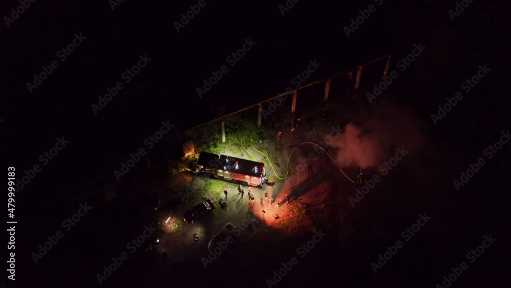Aerial drone shot filming burning car fire and firefighters at work. Road incident. Movie filming area. City safety concept. Aerial drone shot filming burning car fire and firefighters at work. Road incident. Movie filming area. City safety concept.