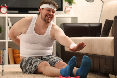 Fitness man lies on thick rug with excess weight  performs stretching exercises