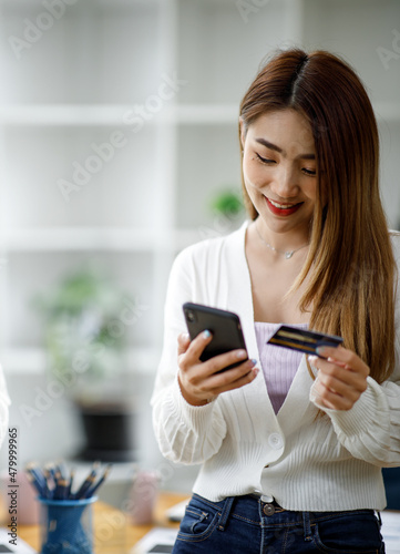 Asian young Business people holding credit cards and using smartphone shopping online payment.