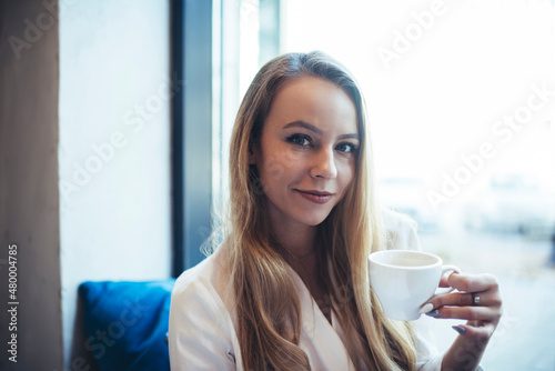 Young smiling woman having hot beverage in cafeteria