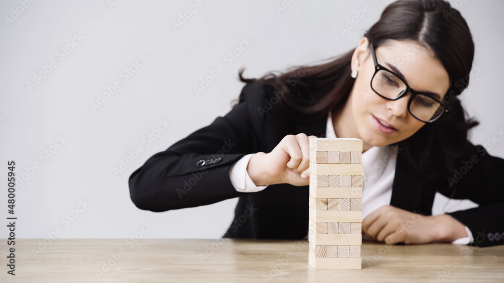 young businesswoman playing blocks wood tower game isolated on grey. young businesswoman playing blocks wood tower game isolated on grey.