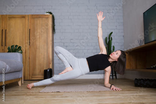young woman stretching and doing yoga fitness exercise in room at home. home fitness, activewear. Healthy and sport lifestyle. 
