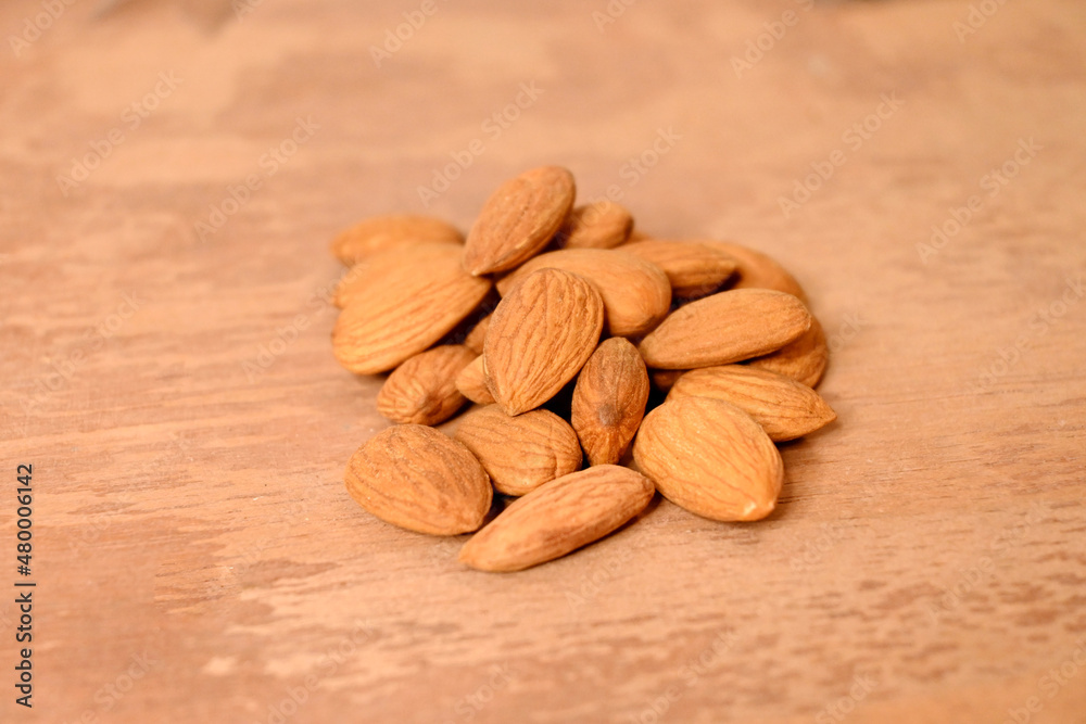 closeup the bunch brown almond nuts over out of focus brown background. closeup the bunch brown almond nuts over out of focus brown background.