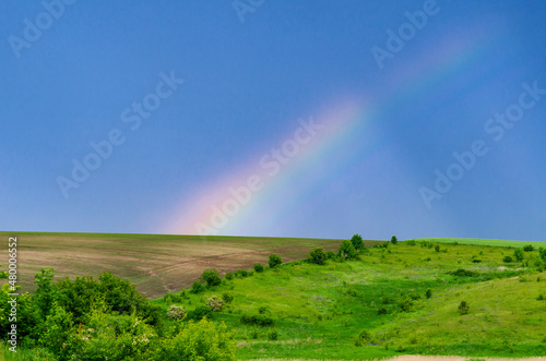 Very beautiful gentle spring photo. Rainbow on the field after rain. Beautiful rainbow wallpaper. Photo for design, inspiration.