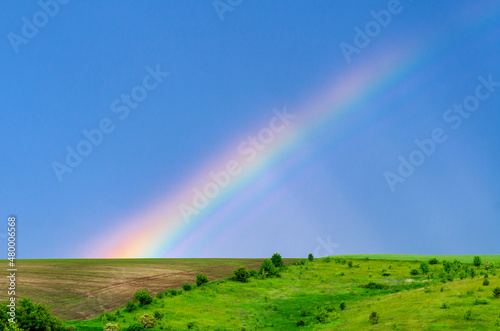 Very beautiful gentle spring photo. Rainbow on the field after rain. Beautiful rainbow wallpaper. Photo for design, inspiration.