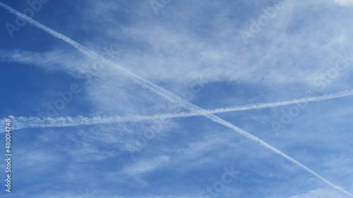 Chemtrail and contrail in the blue sky on a sunny day with space for a message 