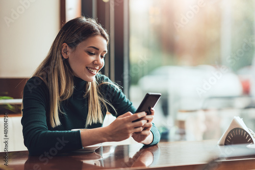 Free Download Young happy woman at restaurant drinking coffee and using mobile phone. - GFXLoad