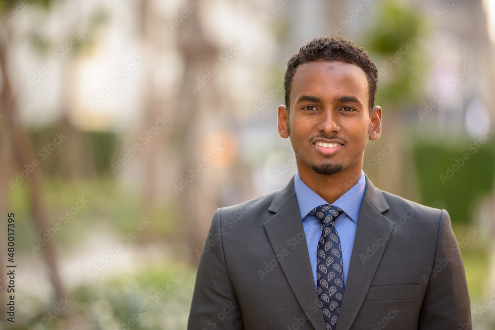 Handsome young black businessman wearing suit in city while smiling Handsome young black businessman wearing suit in city while smiling
