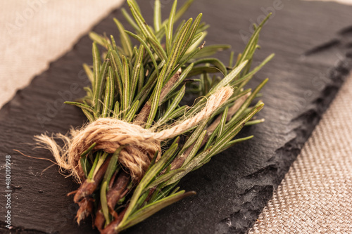 Fresh green Rosemary herb on black stone background, mock up, copy space