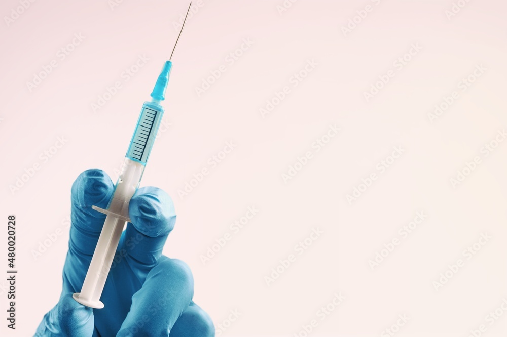 The hand in gloves holding the covid vaccine shot The hand in gloves holding the covid vaccine shot