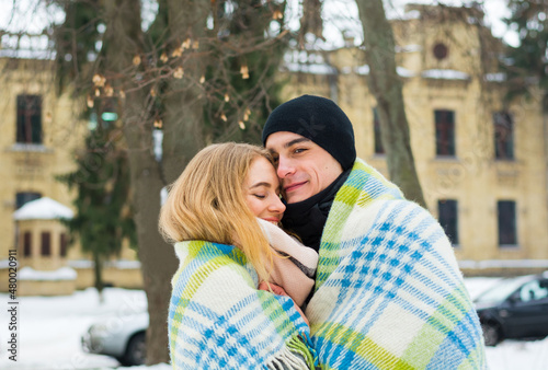 Obraz na płótnie Loving couple in a blanket in winter. The guy hugs a girl on the street in winter. w salonie