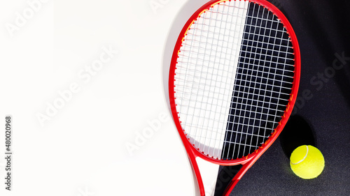 Tennis banner. Sport composition with a tennis racket and a ball on a black and white background with copy space. Sport and healthy lifestyle. The concept of outdoor game sports