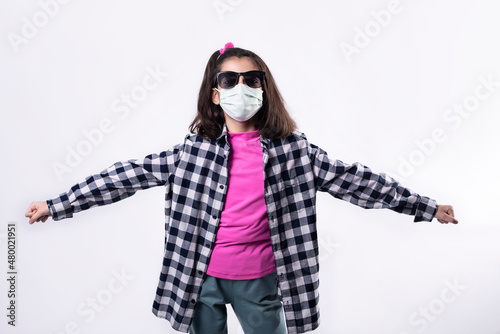 A girl with sunglasses and a surgical mask dances in studio shot in times of pandemic
