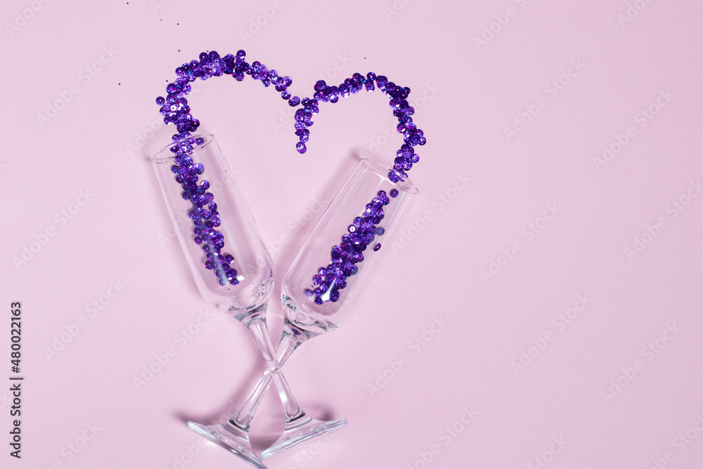 Champagne glass with purple sequins scattered in the form of heart. Valentine's Day design and free space