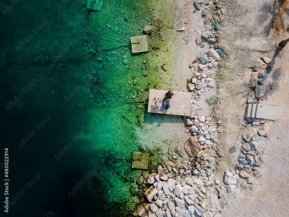 Two people eating breakfast, camping right at the ocean in Split, Croatia at Kasjuni Beach. Aerial drone view.