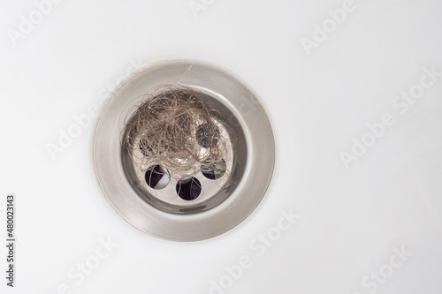 Top view. Clogging of the drain due to loose hair. A bundle of hair is obstructing the sink drain. The problem of hair loss.